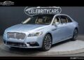 A light blue Lincoln Continental, Coach Door Edition, is parked indoors on a circular platform, boasting a chrome grille and alloy wheels. This exclusive luxury sedan is now for sale.