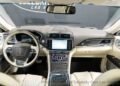 Interior view of the Lincoln Continental Coach Door Edition, featuring a sleek dashboard, steering wheel with controls, touchscreen display, and beige leather seats. This luxurious vehicle is now up for sale.