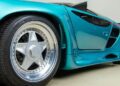 Close-up of a 1993 Vector Avtech WX-3's rear side, showcasing a polished silver wheel with five spokes and sleek bodywork. For sale to enthusiasts who appreciate its striking teal finish and innovative design flair.