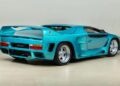 A 1993 Vector Avtech WX-3 sports car, showcasing a stunning teal finish with a large rear spoiler and wide wheels, is viewed from the back and side, displayed indoors. This rare gem is now for sale.