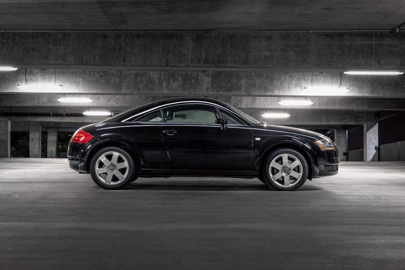An Audi TT parked in a parking garage at night.