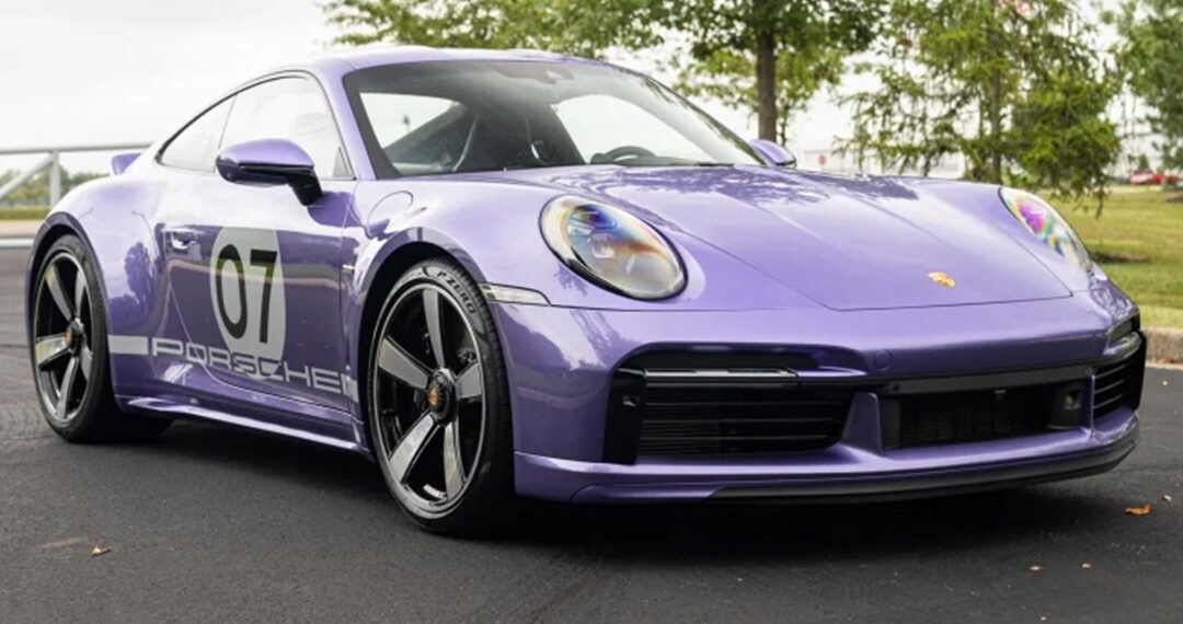 A metallic purple Porsche 911 Sport Classic, marked with the number 07 on its side, sits parked on a paved surface with trees in the background.