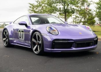 A metallic purple Porsche 911 Sport Classic, marked with the number 07 on its side, sits parked on a paved surface with trees in the background.
