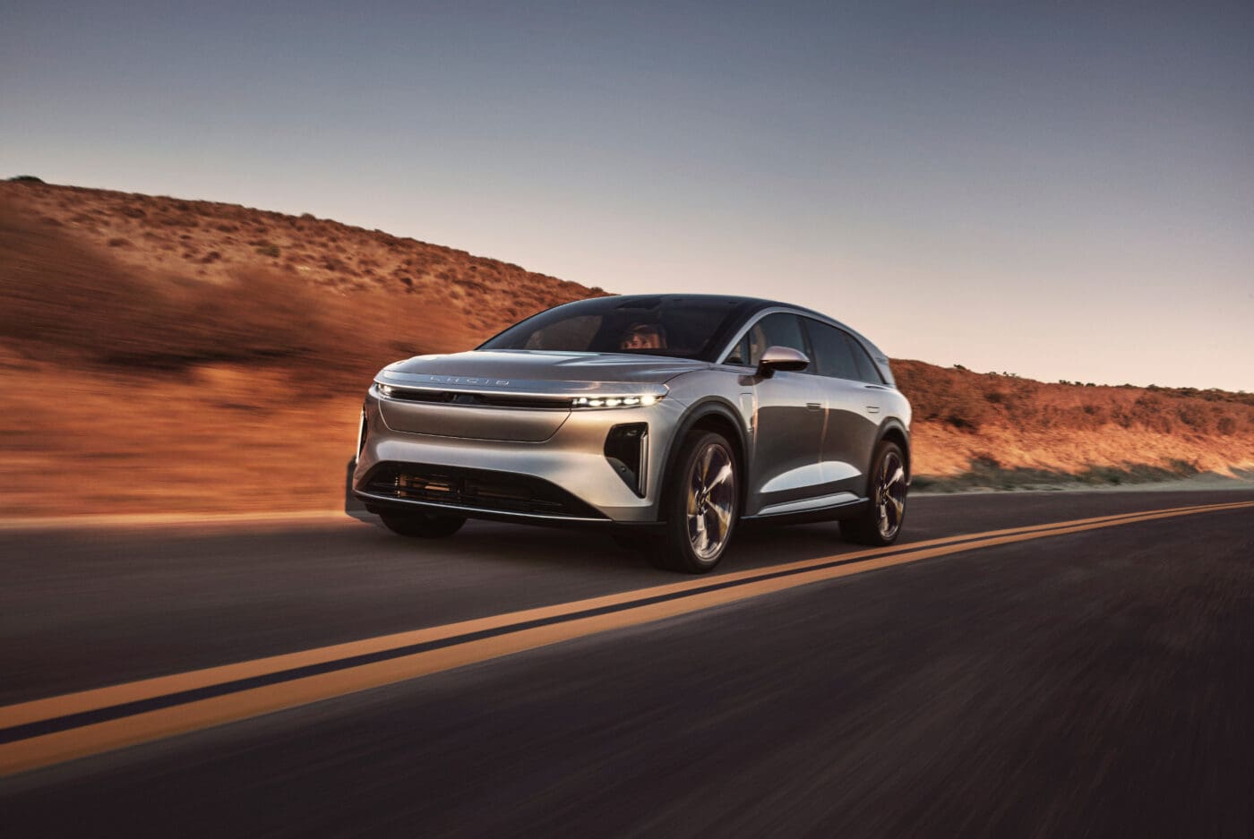 A photo of a Lucid Air Gravity on an empty stretch of road.