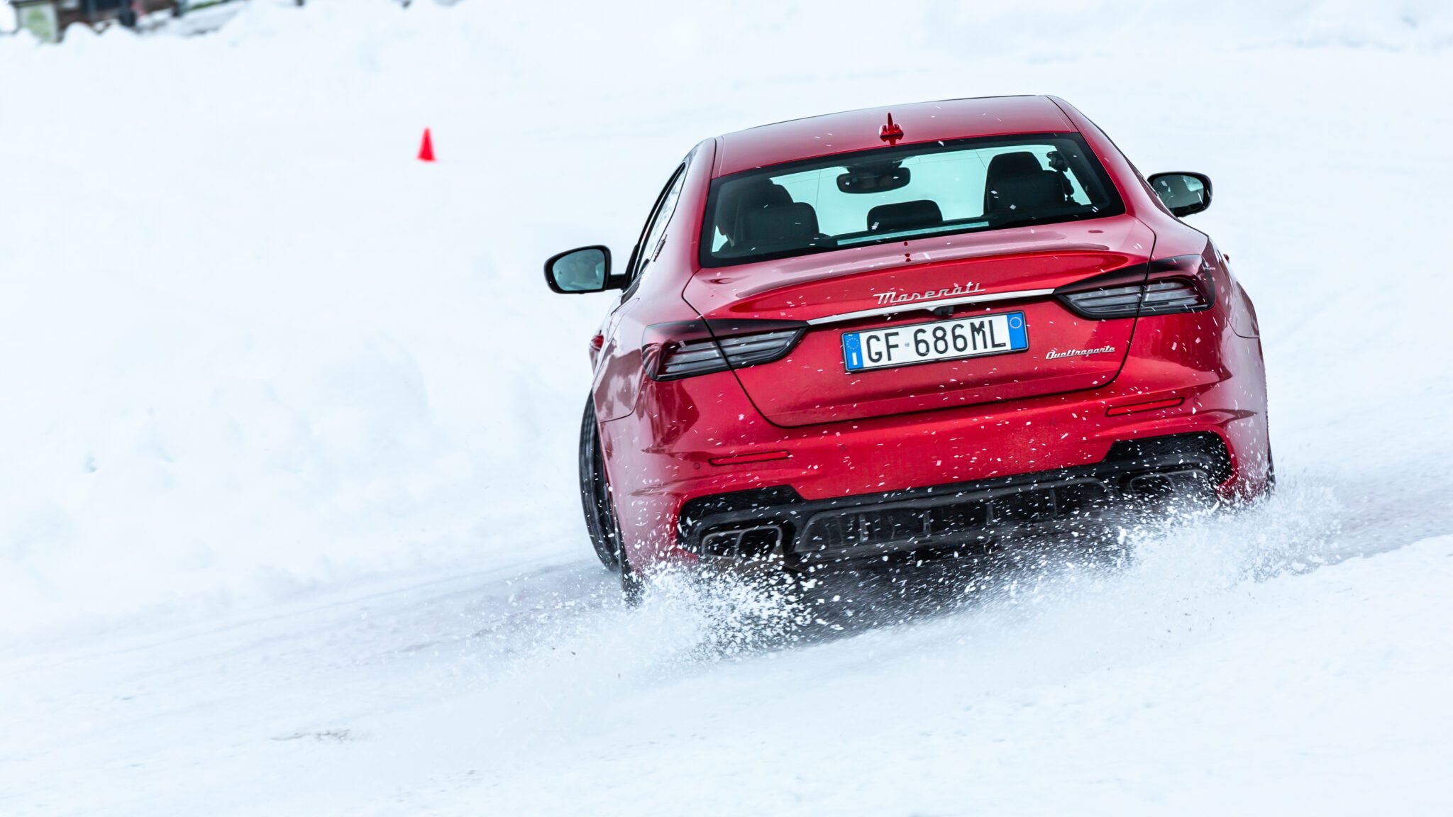 A red Maserati sedan drifting in the snow.