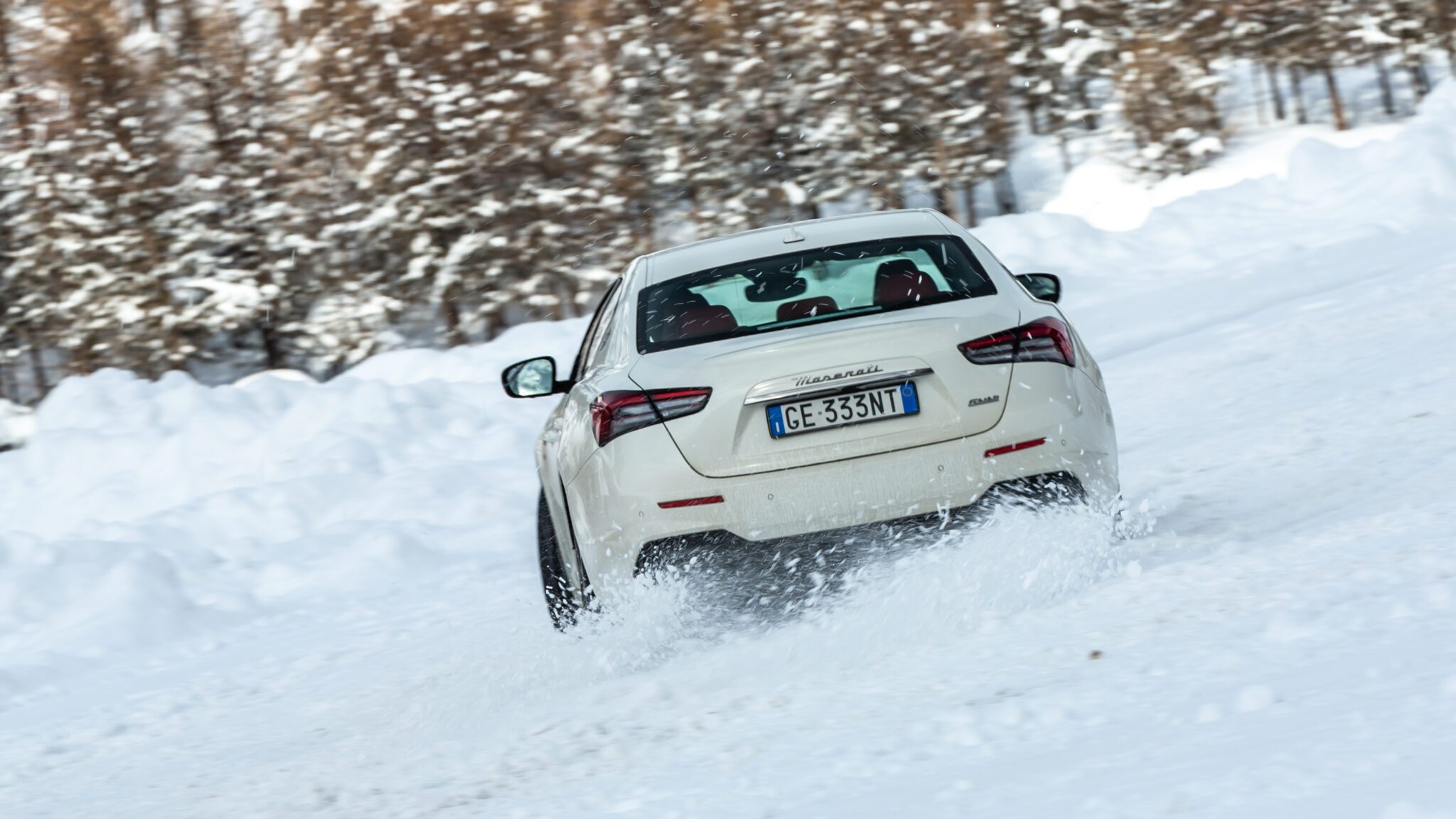 A white Maserati sedan drifting in the snow.