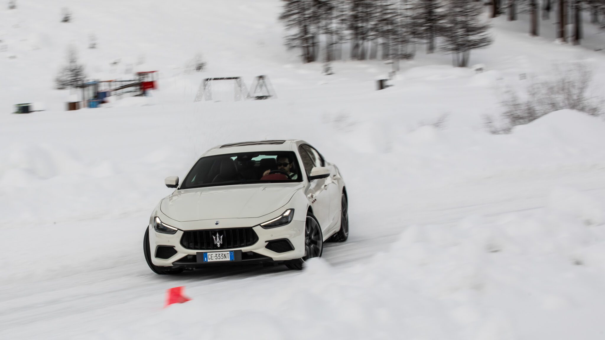 A white Maserati sedan drifting in the snow.