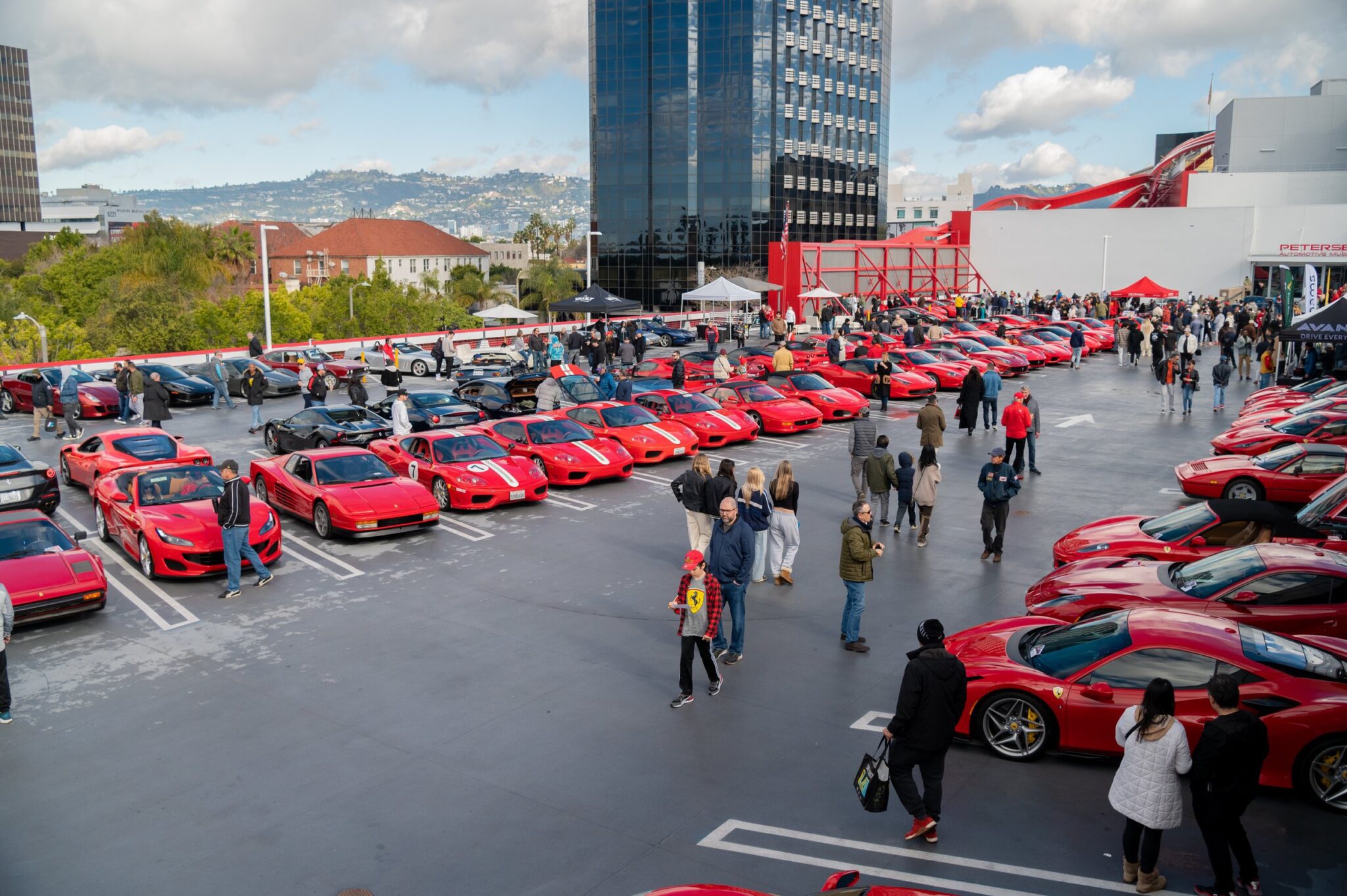 An image of a Ferrari lineup and people walking amongst them.