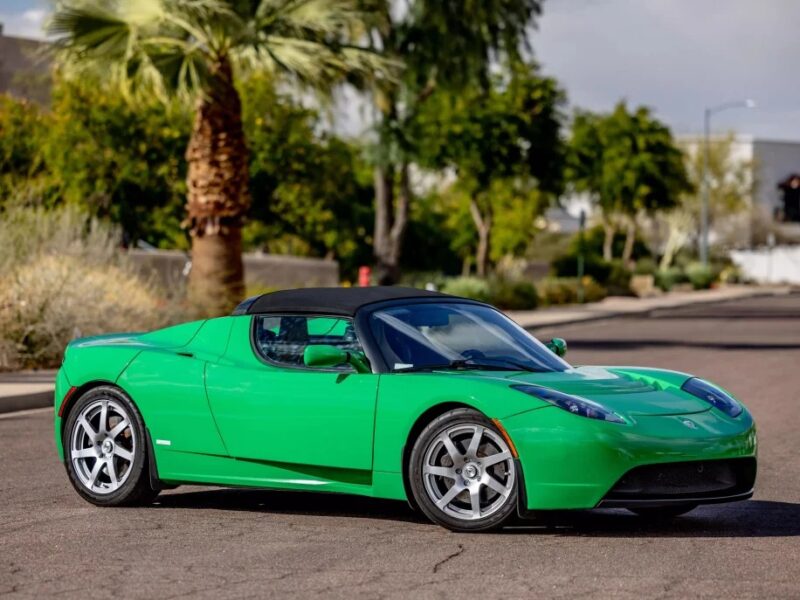 A vibrant green sports car, akin to the festive spirit of St. Patrick's Day, is parked on a road surrounded by lush palm trees and greenery.