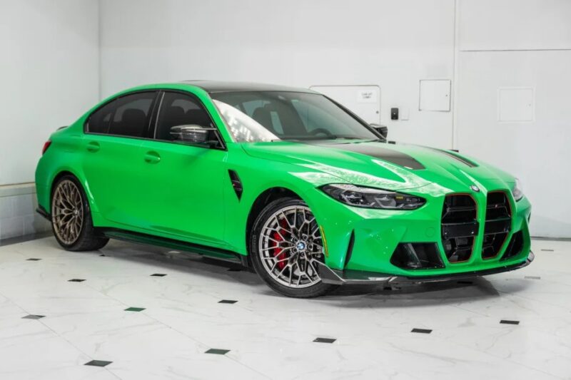 A vivid green sports car with black accents, reminiscent of St. Patrick's Day, is parked indoors on a white tiled floor. It features alloy wheels and a sleek, modern design.