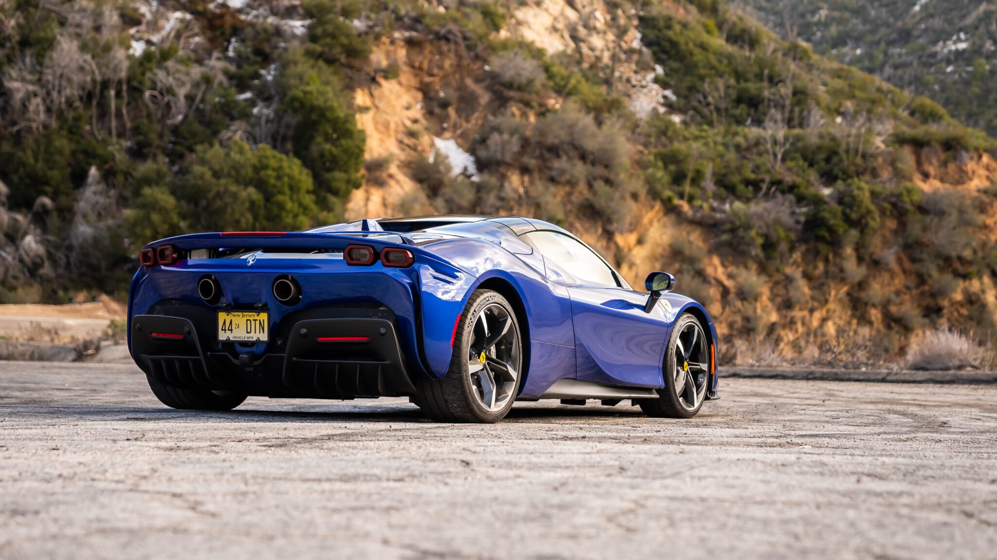 An image of a blue Ferrari SF90 Spider parked outdoors.