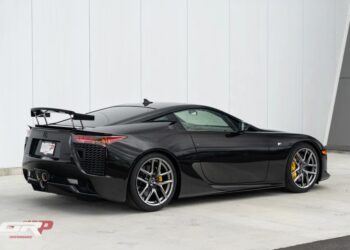 A Japanese supercar masterpiece, the black Lexus LFA boasts a sleek design, rear spoiler, and gleaming silver alloy wheels as it rests elegantly near a white wall.