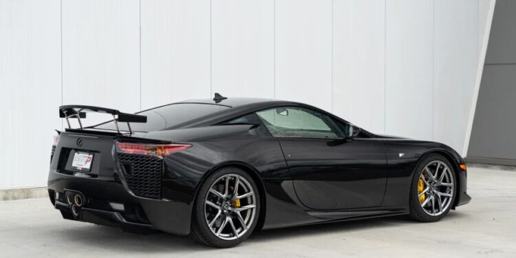 A Japanese supercar masterpiece, the black Lexus LFA boasts a sleek design, rear spoiler, and gleaming silver alloy wheels as it rests elegantly near a white wall.