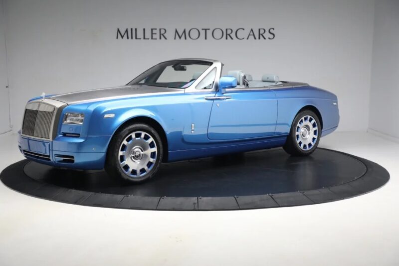 A blue Rolls-Royce Phantom convertible car, the epitome of quintessential luxury, is on display at the Miller Motorcars showroom.