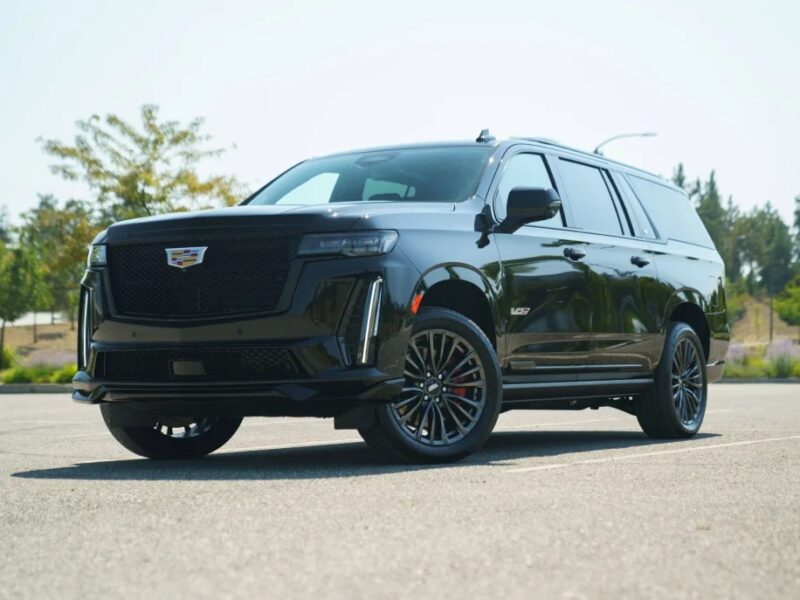 A luxury black SUV parked in an outdoor lot, set against a backdrop of trees and a clear sky, epitomizes the elegance and performance of super SUVs.