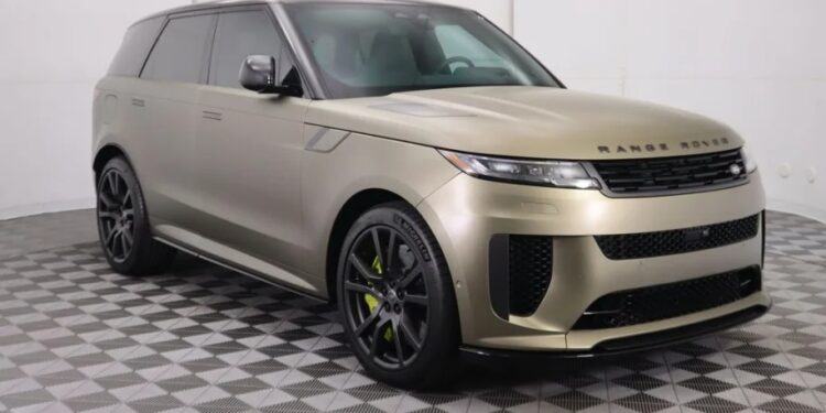 A luxury gold Range Rover SUV glistens on the checkered showroom floor, angled towards the right to showcase its performance-ready stance.