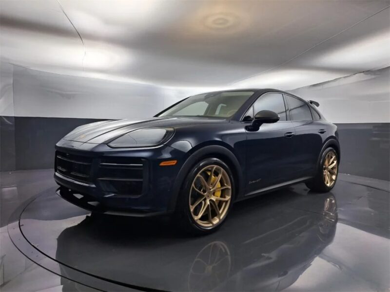 A black sports car with gold alloy wheels is proudly showcased in a well-lit, modern showroom, exuding luxury and performance.