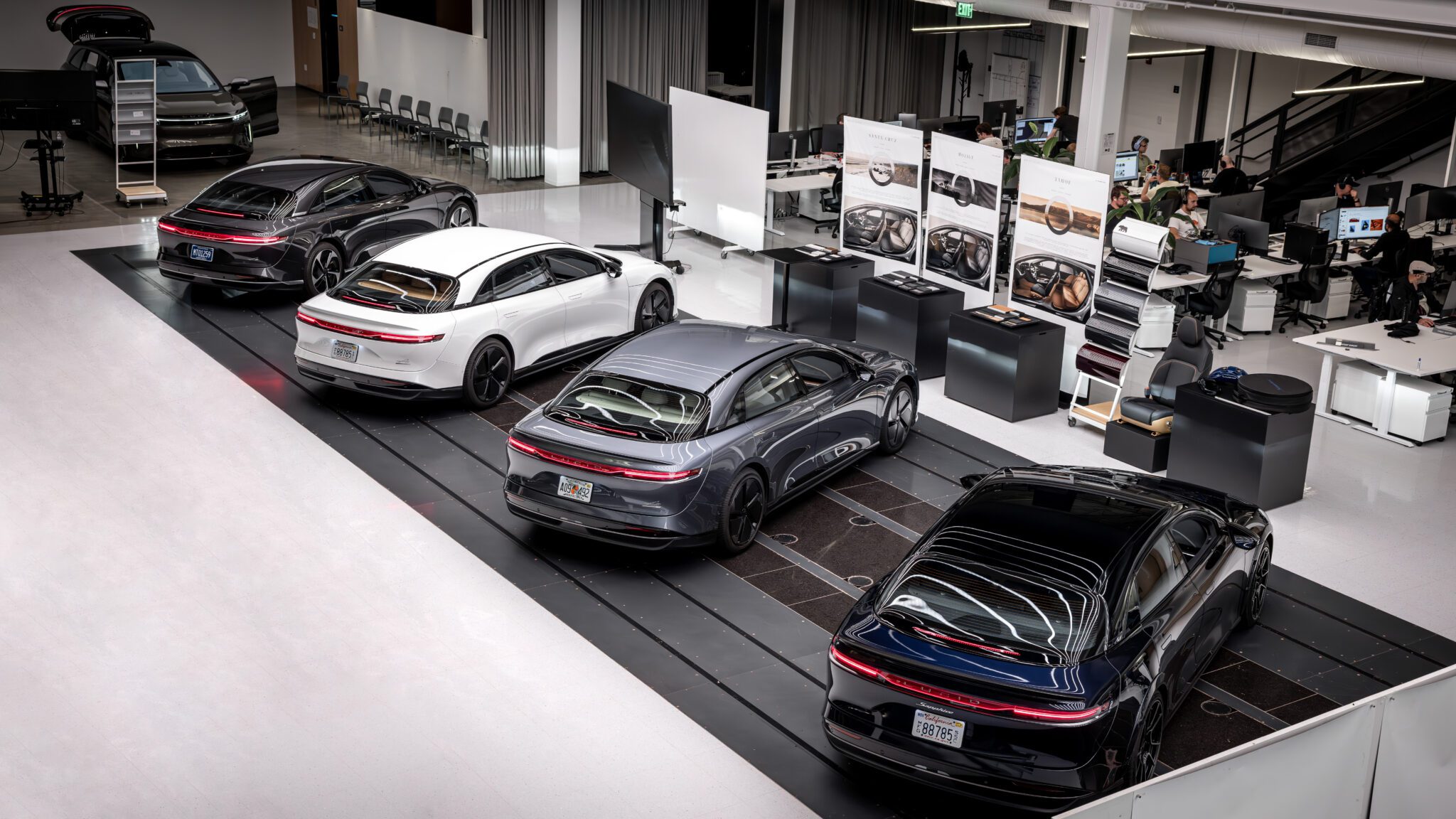 An image containing four cars in a factory floor.