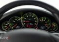 Close-up view of a 2012 RUF Rt 12 R dashboard with five circular gauges, including speedometer, tachometer, fuel, and temperature indicators. Red warning lights and digital displays highlight this ultra-rare performance car.