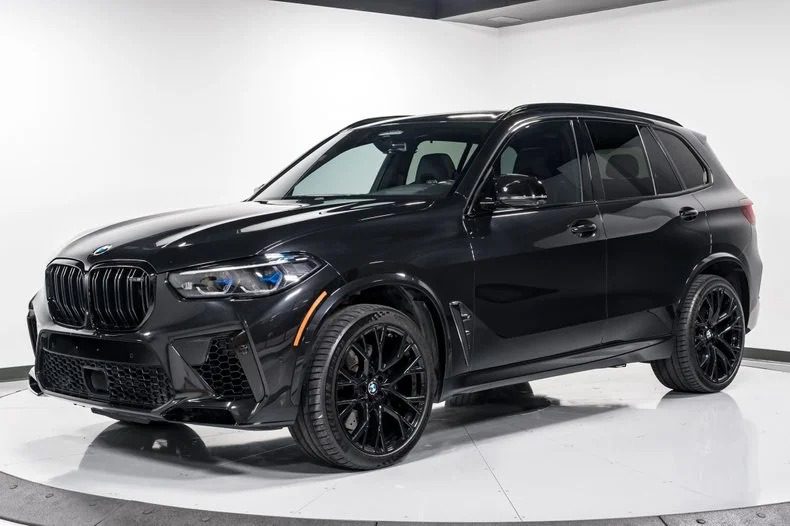 Juodas „BMW X5“ visureigis yra pastatytas patalpose ant baltos platformos, pastatytas prie paprastos baltos sienos ir lubų - ryškus pavyzdys tarp parduodamų prabangių visureigių.