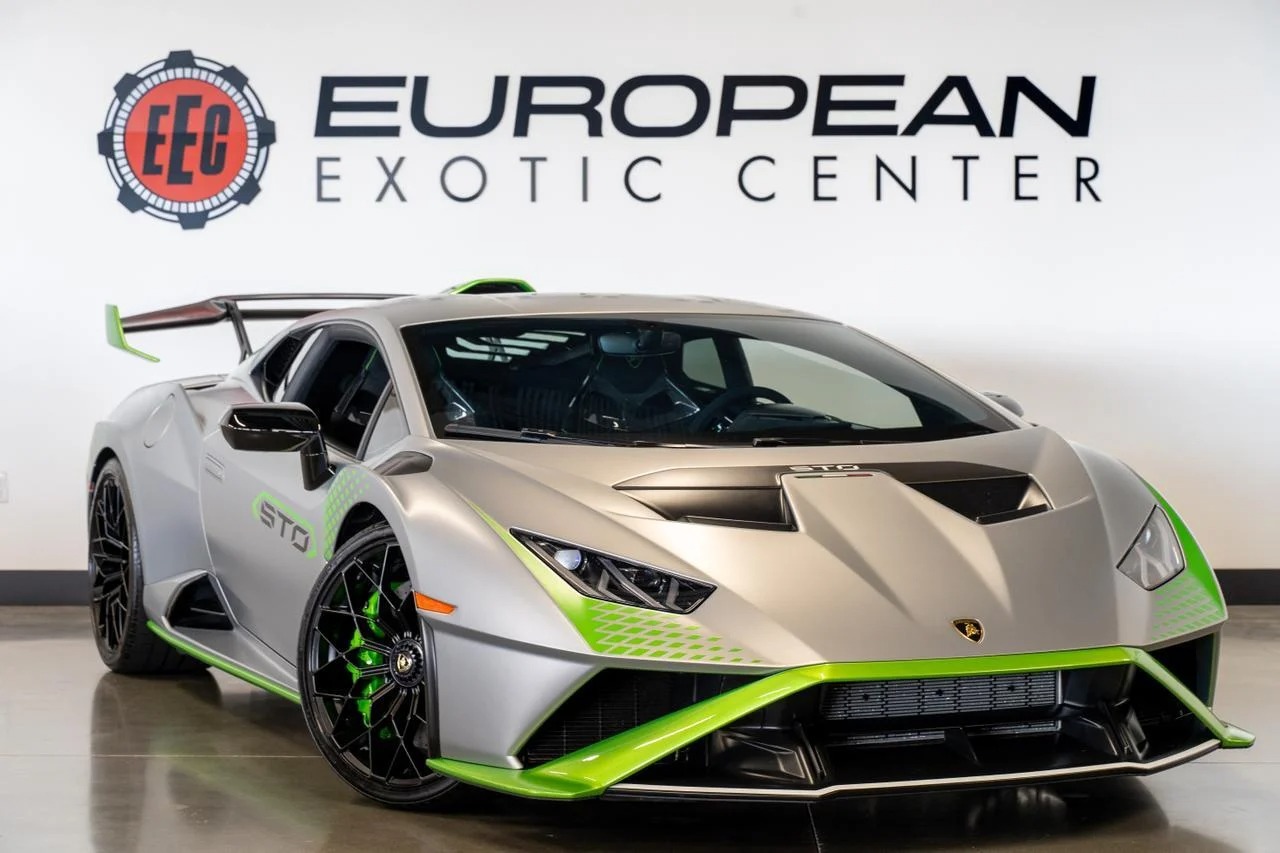 A silver Lamborghini Huracán STO with green accents, an iconic supercar, is parked indoors in front of a sign that reads "European Exotic Center.
