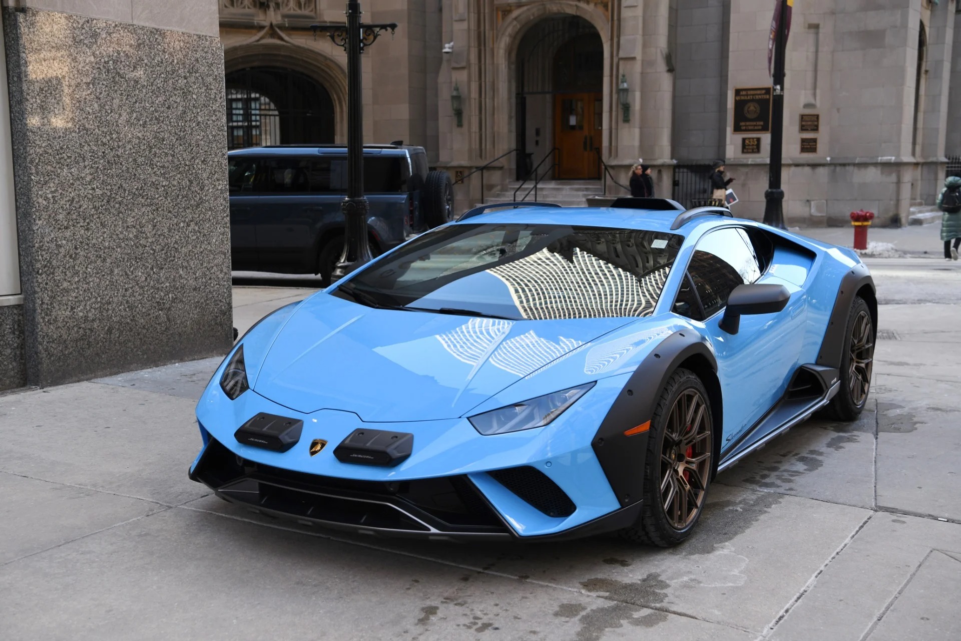 A blue Lamborghini supercar is parked on a city street in front of a historic stone building, showcasing the iconic style of Lamborghinis for sale.