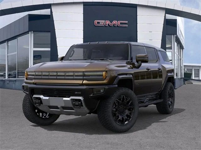 Tamsios spalvos „GMC Hummer EV“ visureigis, vienas įspūdingiausių įperkamų prabangių visureigių, yra pastatytas priešais GMC prekybos pastatą aiškią dieną.