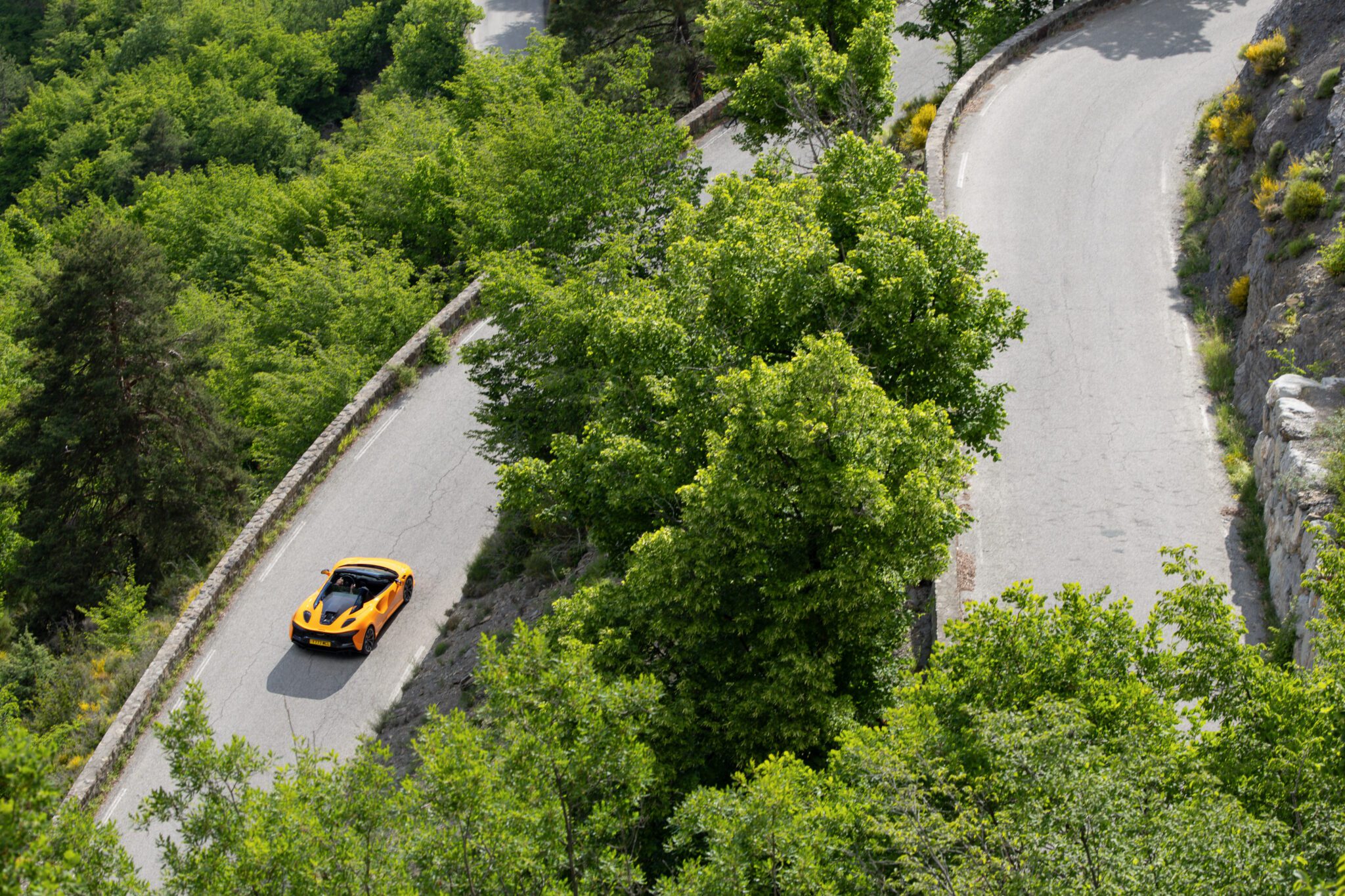 An image of a McLaren Artura Spider driving on a mountain road.