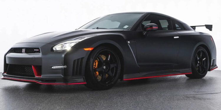 A black Nissan GT-R sports car with red accents and a rear wing is parked in a plain indoor setting, featured as part of the dealer spotlight at OpenRoad Northwest—your destination for exotics for sale.