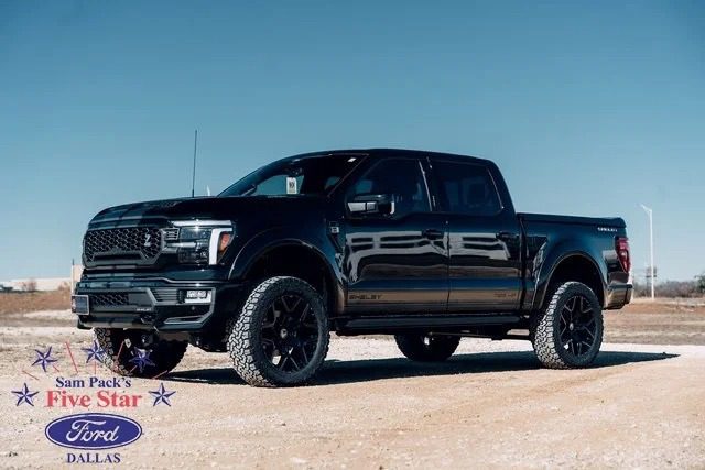 A sleek black Ford F-150 pickup truck is parked on a dirt road under a clear blue sky. The logo for Sam Pack's Five Star Ford Dallas graces the bottom left corner, highlighting their renowned range, including Shelby Trucks.