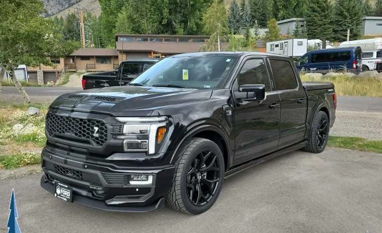 A sleek Ford F-150 pickup truck is parked in a lot, surrounded by trees and buildings, ready to conquer any journey.