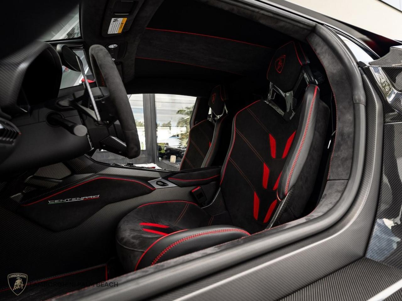 Interior view of a Lamborghini Centenario, showcasing its luxury sports car appeal with black and red upholstery, bucket seats, and a high-tech dashboard. The Giallo Midas accents enhance the elegance—this masterpiece is now for sale.