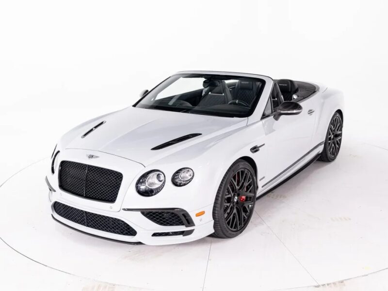 The sleek Bentley Continental GT convertible, a true luxury tourer, boasts black accents and an open top, showcased elegantly against a pristine white backdrop.
