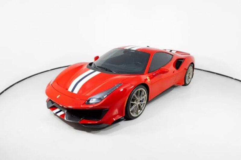 A track-ready, red Ferrari 488 Pistas with white and blue stripes graces a well-lit studio, its prancing horse emblem gleaming against the pristine white backdrop.