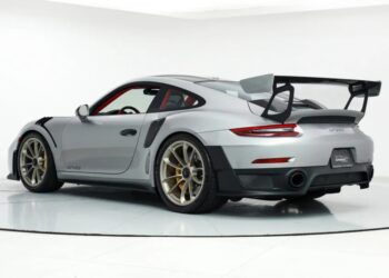 A silver Porsche GT3 RS sports car, known as the ultimate speed machine, features a large rear spoiler and gold alloy wheels, viewed from the rear three-quarter angle in a white studio setting.