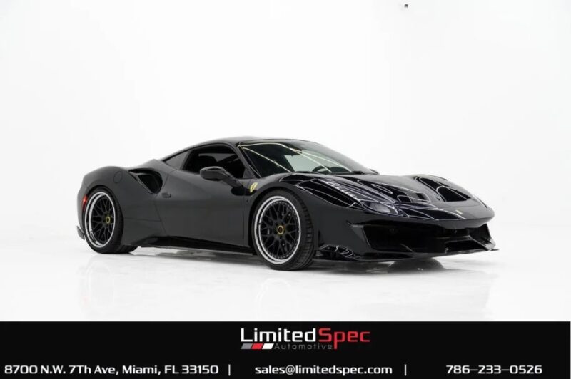 A sleek black Ferrari 488 Pista sports car, track-ready and displayed indoors on a pristine white background, with LimitedSpec Automotive contact details featured below.