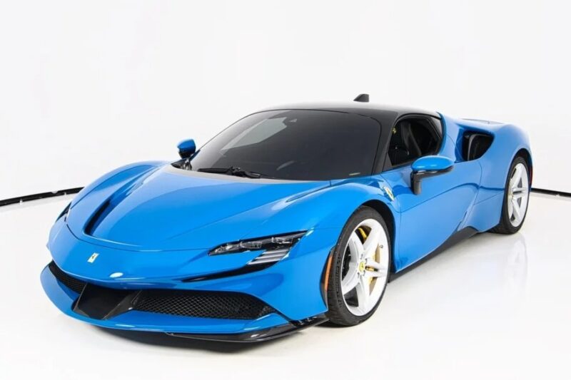 A Ferrari-inspired blue sports car boasts a sleek design and aerodynamic body, featuring contrasting white wheels. It is artfully parked in a pristine studio, with the minimalist white background accentuating its vivid colors for sale.