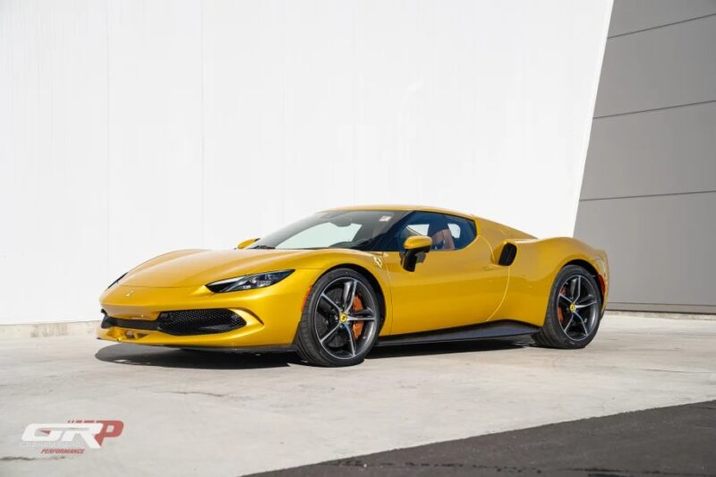 A vibrant yellow Ferrari sports car is parked in front of a stylish white and gray wall, capturing a perfect blend of colors.