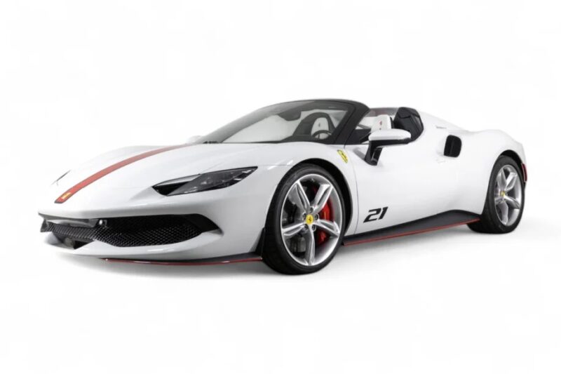 A white Ferrari sports car with a bold red stripe down the center and the number 21 on the side boasts black accents. This sleek, aerodynamic design features a convertible top, making it an irresistible choice for any enthusiast looking for style and performance on sale.