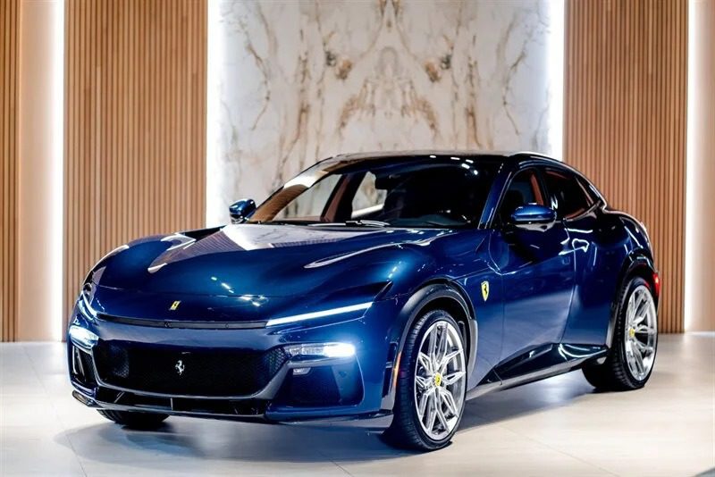 A sleek, blue Ferrari is on display in the showroom, its vibrant color contrasting elegantly with the wood-paneled and marble walls, hinting at an exclusive sale.