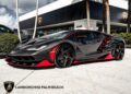 A sleek black Lamborghini with red accents is parked in front of Lamborghini Palm Beach, where a stunning 2017 Lamborghini Centenario is also for sale.