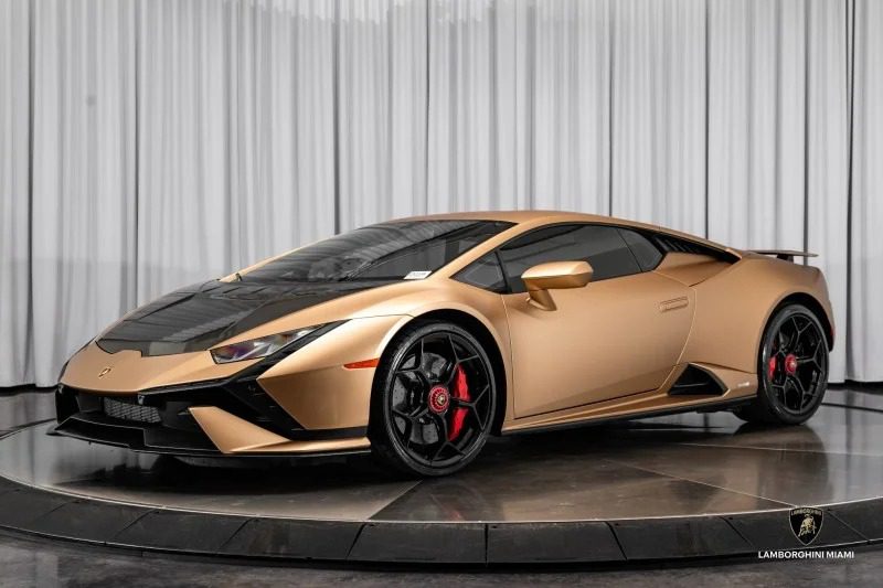 A gold Lamborghini Huracan Tecnica sports car is on display in the showroom, featuring striking red brake calipers and sleek black accents.