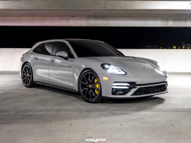 A sleek gray sports car, reminiscent of high-end luxury performance wagons, is parked in a dimly lit garage, showcasing its aerodynamic design and black alloy wheels with yellow brake calipers.