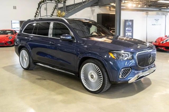 A luxury blue Mercedes-Benz SUV with a sleek design, featuring large chrome wheels, is showcased indoors in a showroom, available for sale.