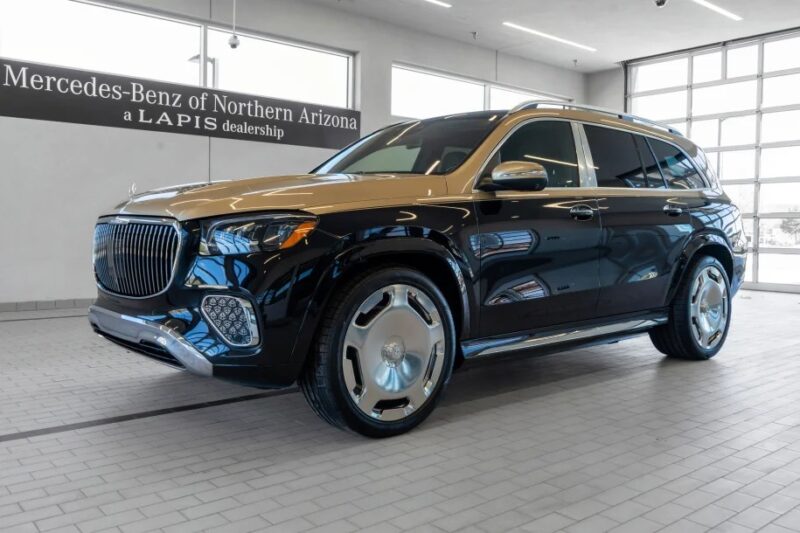 A black and tan Mercedes-Benz SUV, epitomizing luxury, is beautifully showcased inside the dealership showroom with a sign for Mercedes-Benz of Northern Arizona.