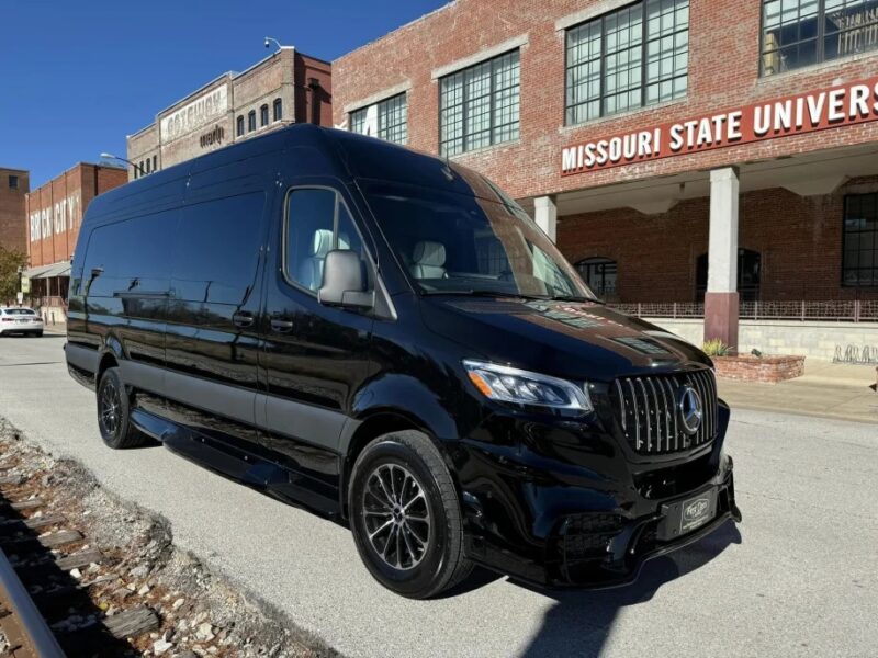 A black Mercedes-Benz van is parked in front of the Missouri State University buildings on a sunny day, adding a touch of luxury to the scene.