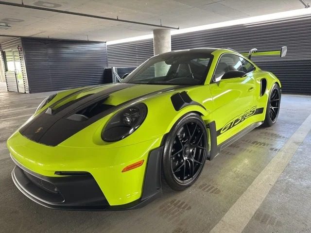 A bright green Porsche 911 GT3 RS with sleek black accents is parked in the garage, embodying Porsche's ultimate driver's car experience.