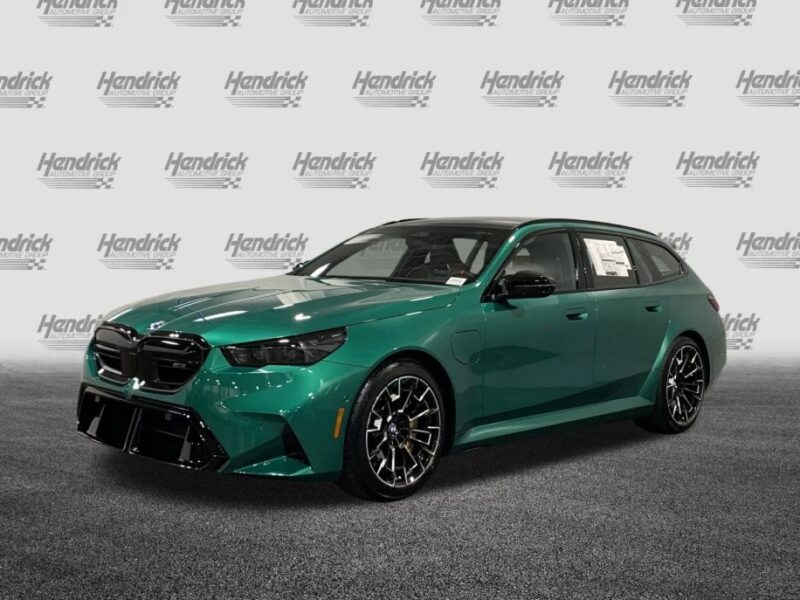 The luxury green BMW station wagon stands proudly on a carpeted floor, set against a Hendrick branded backdrop, exemplifying both style and performance.