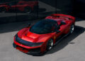 A red Ferrari with a sleek design, embodying the essence of a hypercar, is parked on a paved surface, reflecting off a mirrored glass wall.