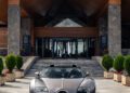 A sleek silver Bugatti hypercar is parked in front of a large modern house with wooden and stone features, reminiscent of the luxurious style found in Morocco.